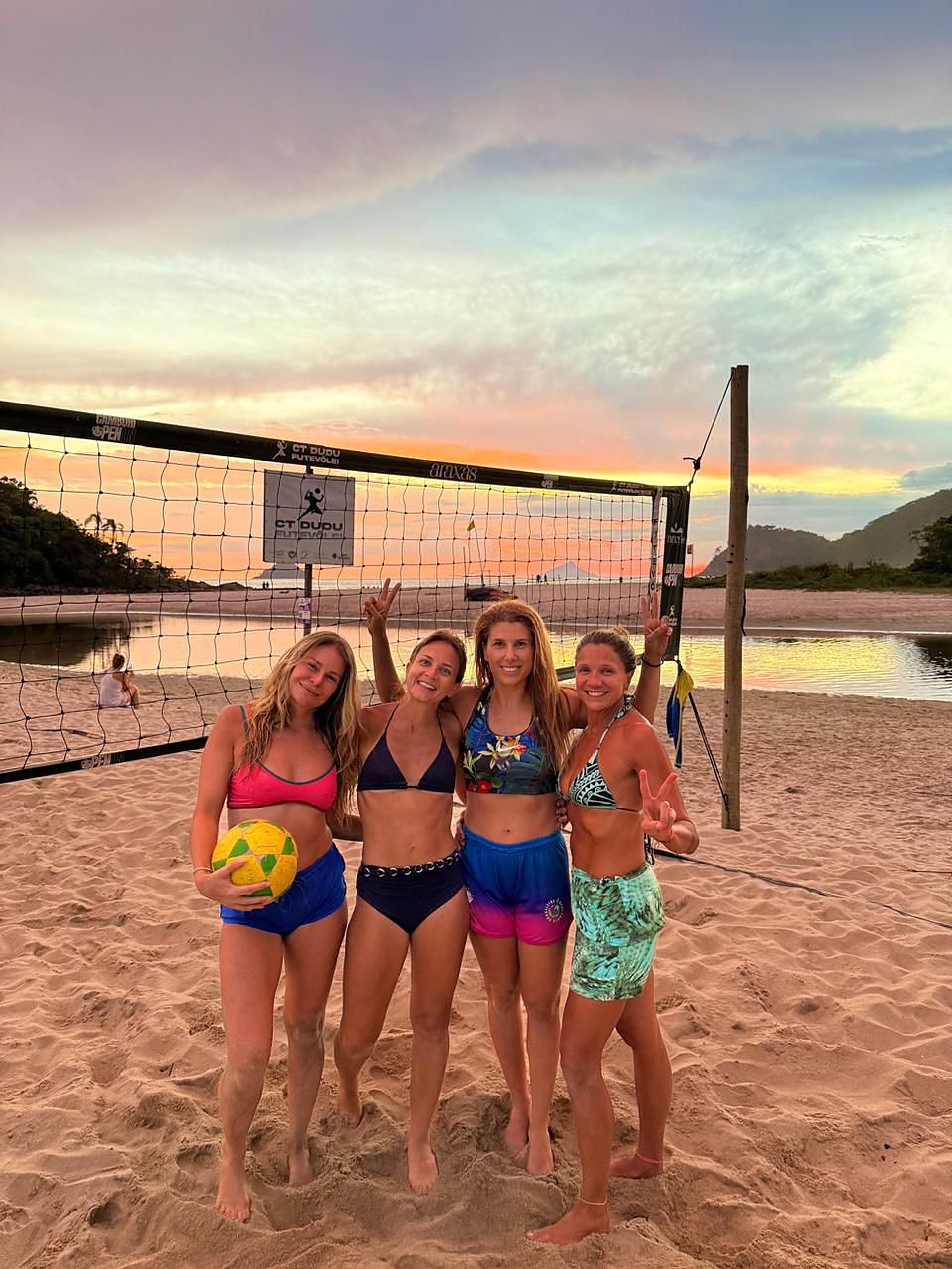 Turma de alunas do CT Dudu Futevôlei posando na quadra ao pôr do sol