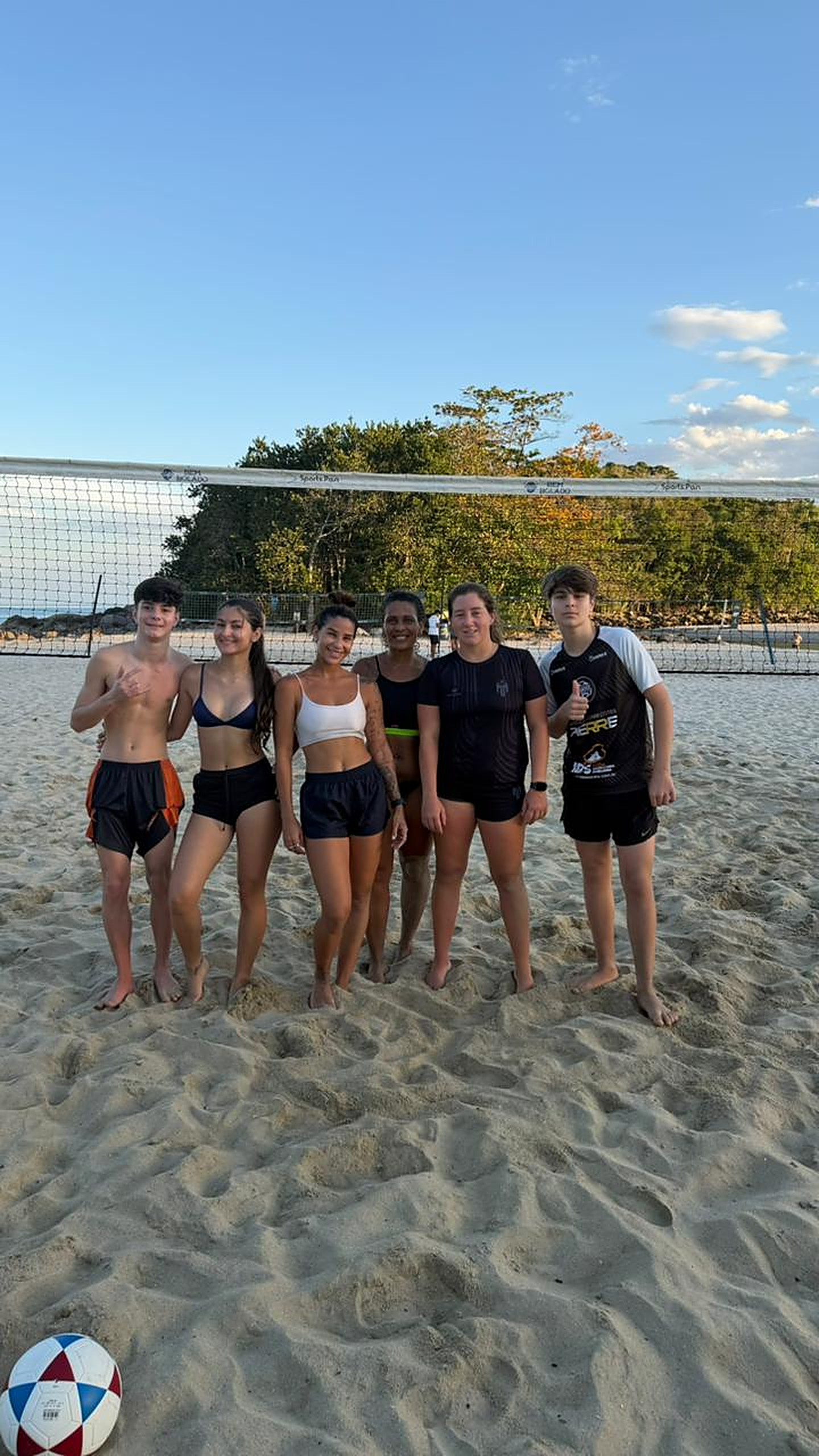 Turma de alunos e alunas do CT Dudu Futevôlei em frente à rede